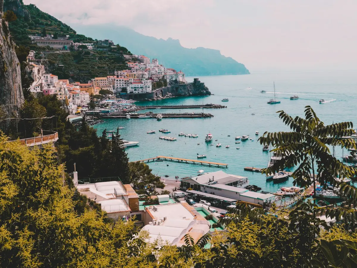 A Mediterranean coastal town on the cliffs above a boat-filled harbour.