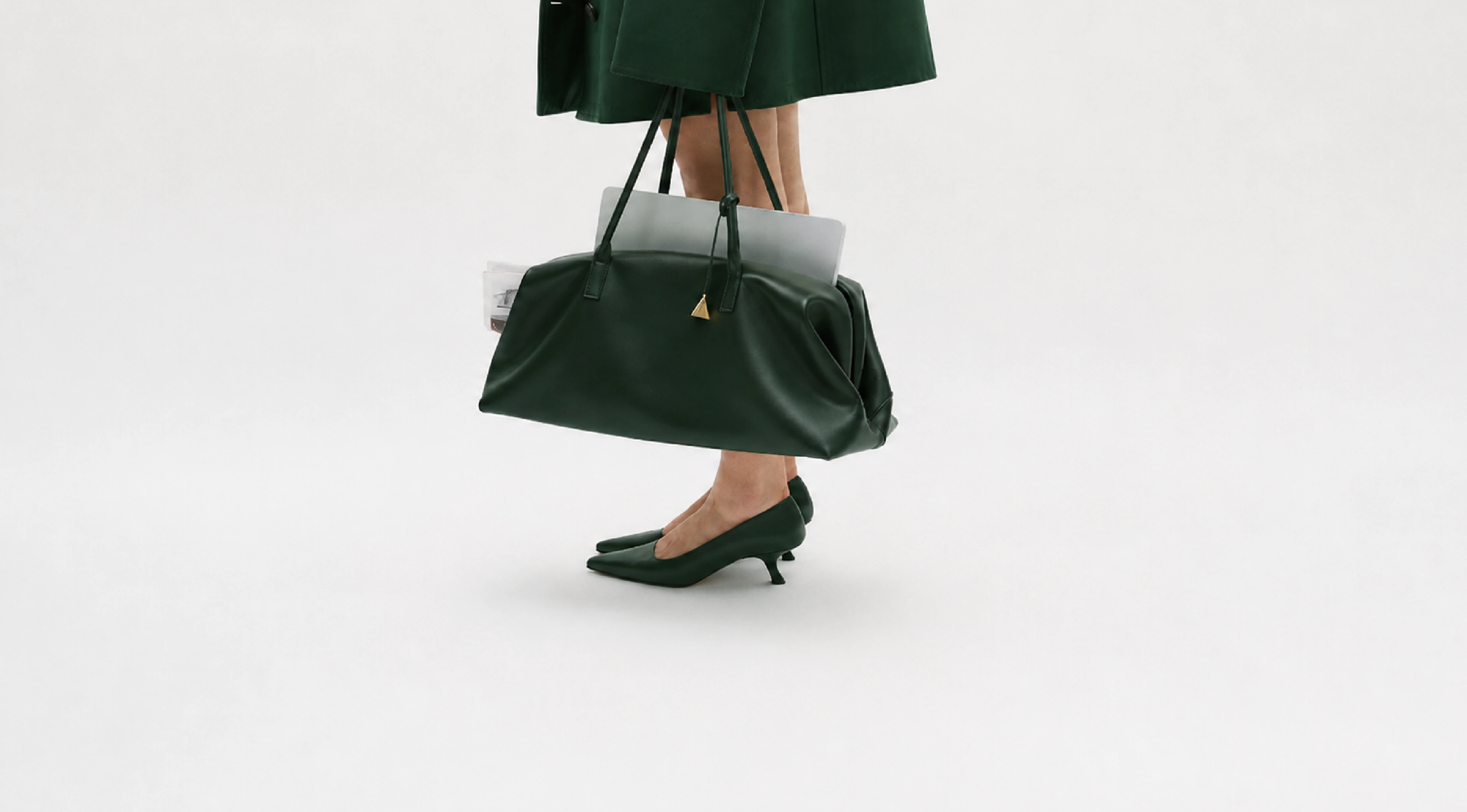 A woman carrying an evergreen leather bag and wearing matching shoes.